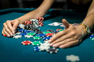 pretty young woman in elegent blck dress gambling on casino green table