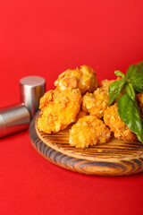 Board with tasty popcorn chicken and spices on color background