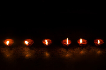 Group of decorated diyas on black background during Diwali