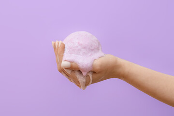 Female hand with dissolving bath bomb on color background, closeup