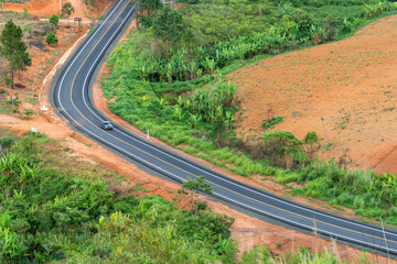 Top view of car on no car road on a background of green forest and foothills
