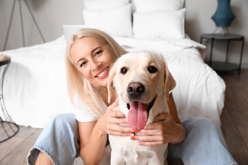 Mature woman with cute Labrador dog in bedroom