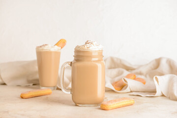Mason jar and glass of tasty Tiramisu Latte on table