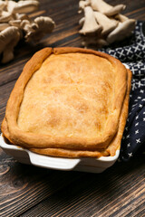 Baking dish with tasty mushroom pot pie on wooden background