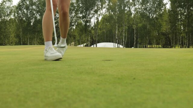 Beautiful woman golfer prepare to shot on ball on the green golf course.