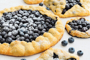 Tasty blueberry galettes on light background, closeup