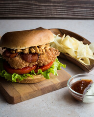 Lettuce, tomato, bacon and crispy chicken burger with fried yucca and sauces