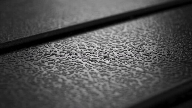 Black textured plastic grungy material with ragged natural pattern. Macro. Dolly shot