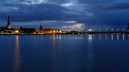 Fototapeta na wymiar Autumn dawn in blue tones over old Riga reflection of night lights in the Daugava