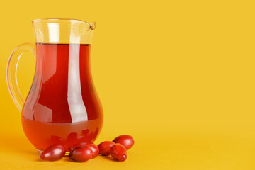 Jug of healthy dogwood berry drink on color background
