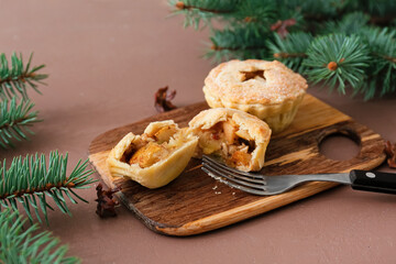 Board with tasty mince pies and fork on color background