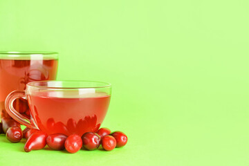 Cups of healthy dogwood berry drink on color background