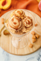 Glass bowl of tasty caramel ice cream on table