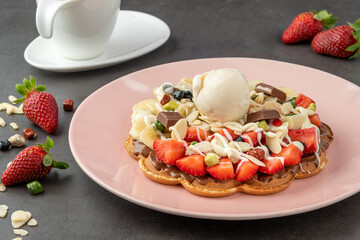 Heart waffle with banana and strawberry with gummy candy and ice cream on it.