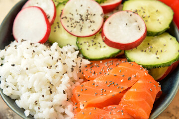 Tasty poke bowl with salmon and vegetables on table, closeup