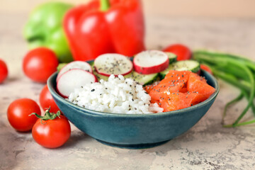 Bowl with tasty rice, salmon and vegetables on color background, closeup