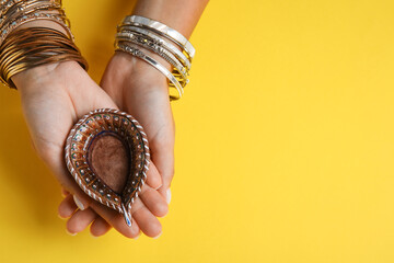 Female hands with diya lamp for Diwali on color background