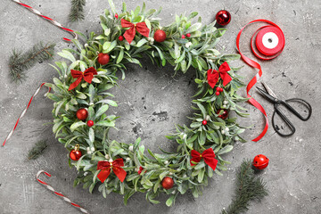 Beautiful mistletoe wreath and scissors on grunge background
