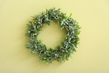 Simple mistletoe wreath on color wall