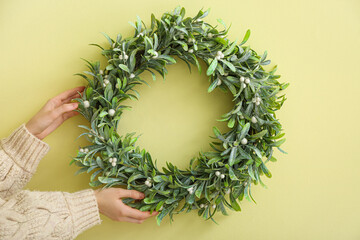 Beautiful mistletoe wreath on color wall