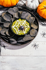 Spooky Halloween black potato chips with guacamole dip
