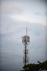 Pylon of Telecommunications with antennas for radio, television and telephone signal broadcasting in a cloudy blue sky. 
