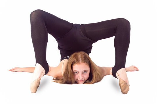 Sport Ideas and Concepts. Young Caucasian Sportswoman Rhythmic Gymnast In Training Black Outfit During Backward Legs Twist Stretching Exercises While Laying on Floor On White.