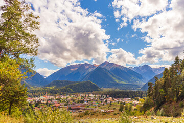 mountain meadow in morning light. countryside springtime landscape with valley in fog behind the forest on the grassy hill. fluffy clouds on a bright blue sky. nature freshness concept