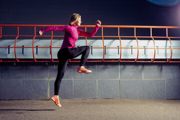 Professional Mature Female Runner in Jogging Outfit During Running Training in Evening City Environment