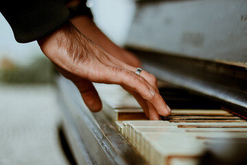 The man plays the piano. Lifestyle. Musical instrument on the street. Hand and piano keys close up. Creative life.