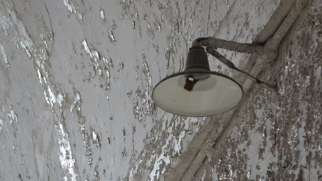 Close-up of light fixture with cracked plaster wall in background.