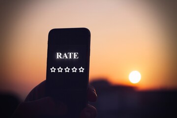 Silhouette of a cellphone at sunset, with the display showing the 5 stars symbol for rating a vacation.