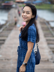 Fototapeta premium Young beautiful asian woman at Auttamanusorn Wooden Bridge (Sapan Mon) Kanchanaburi , Thailand when she have holiday vacation