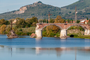 The broken bridge of Calcinaia, Pisa, Italy, with the new church of Castellare in the background - obrazy, fototapety, plakaty