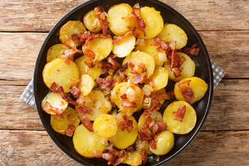 Bratkartoffeln German Cottage Fries With Bacon and Onion close up in the plate on the table. Horizontal top view from above