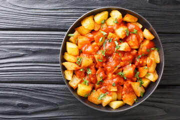 Patatas Bravas recipe fried potatoes with bravas sauce close up in the plate on the table....