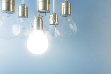 Glowing light bulb on blurry blue wall background. Idea, innovation, solution and invention concept. Mock up, 3D Rendering.