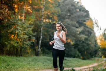 Woman running in autumn fall forest. Healthy lifestyle . Fit ethnic Caucasian fitness model.