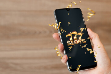 Online casino, smartphone with slot machine with jackpot and gold coins. Online Slots, Lucky Seven 777, Dark Gold Style. Luck concept, gambling, jackpot, banner.