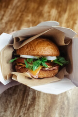 Close-up of a standard burger. Adult fast food in a restaurant or cafe. Macro photo of burger ingredients with meat, cheese and herbs. Eco burgers for the whole family
