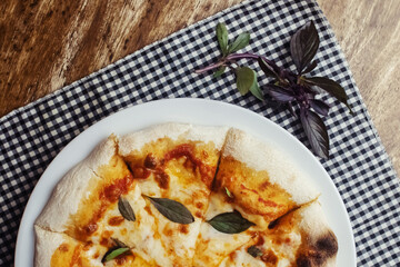 Close-up of Margarita pizza in a disposable dish. Top view of takeaway food in a fast food cafe. On photo - mozzarella cheese, tomatoes, and red basil. The classic recipe. Food for family and friends.