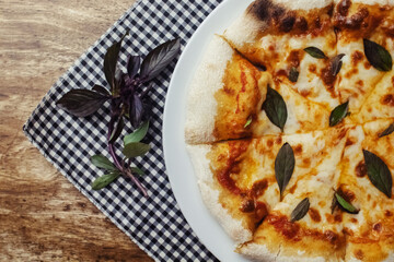 Close-up of Margarita pizza in a disposable dish. Top view of takeaway food in a fast food cafe. On photo - mozzarella cheese, tomatoes, and red basil. The classic recipe. Food for family and friends.