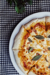 Close-up of Margarita pizza in a disposable dish. Top view of takeaway food in a fast food cafe. On photo - mozzarella cheese, tomatoes, and red basil. The classic recipe. Food for family and friends.