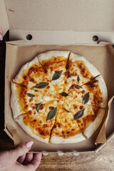 Close-up of Margarita pizza in a disposable dish. Top view of takeaway food in a fast food cafe. On photo - mozzarella cheese, tomatoes, and red basil. The classic recipe. Food for family and friends.