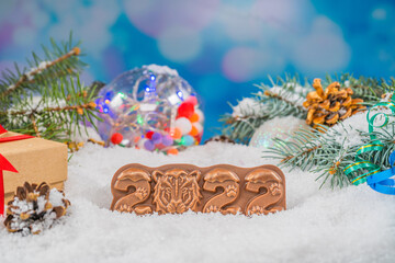 Christmas chocolate figure on snow. chocolate figurine shape 2022. New Year's composition