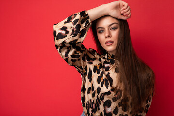 Fashion photo of young beautiful fashionable sexy brunette woman wearing stylish leopard blouse isolated on red background with empty space