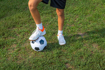Boy teen puts his leg on ball on soccer field.