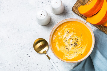Pumpkin soup puree with cream in the bowl. Top view image at white table.