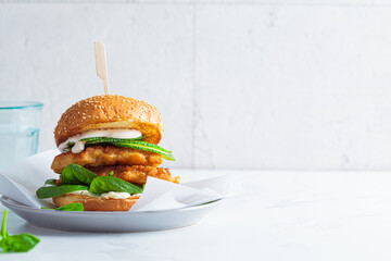 Fish burger on a gray plate. Cod fish in batter with mayonnaise and spinach sandwich.