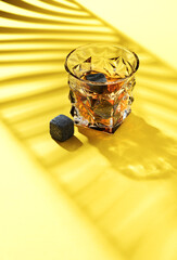 Hard strong alcoholic drinks in glass: cognac, tequila, scotch, brandy or whiskey on a yellow background with hard lights and shadows, top view